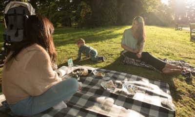 Two women and a baby enjoy a picnic on a blanket