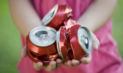 person holding crushed soda cans