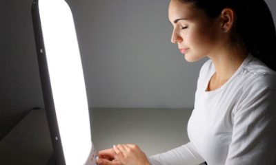 Young woman sits in front of bright light for therapy