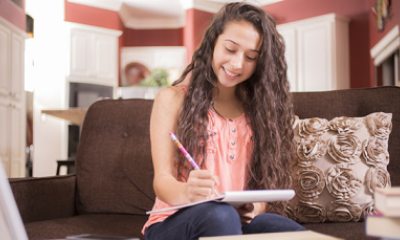 teen girl writing in a notebook at home