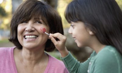 Young person paints heart on cheek of older person