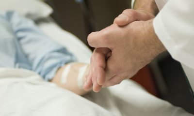 Provider clasps hand of patient in hospital bed
