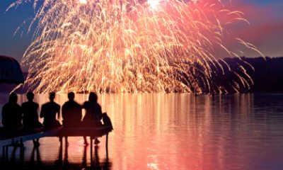 Silhouette of group of people watching fireworks from a dock