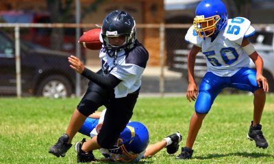 A youth football player runs with a ball around defenders during a game