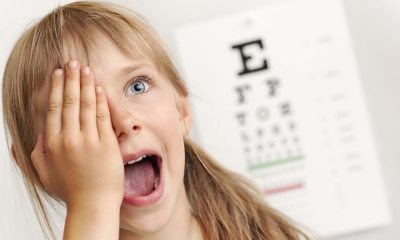 A young child covers one eye while at the eye doctor's office