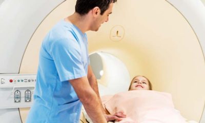 A Child speaks with a healthcare provider while preparing for a scan in an MRI machine