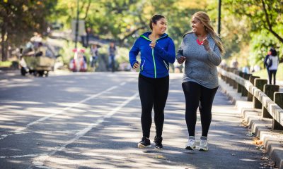 Two women jogging down the street and smiling at each other