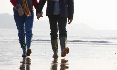 A couple holding hands and walking on the beach