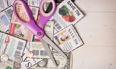 Purple handled scissors laying over clipped coupons