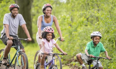 A family with helmets on, smile while enjoy a bicycle ride