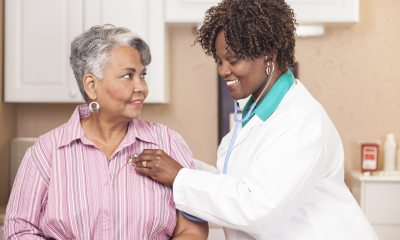 A healthcare provider smiles and checks a patient's heart rate