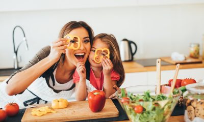 A woman and younger girl hold cut-out sweet bell peppers over their eyes and laugh