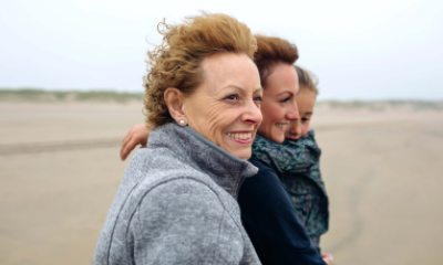 Three generations of women walking on the beach and smiling