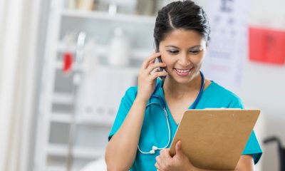 A nurse reading a patient chart and speaking on a phone