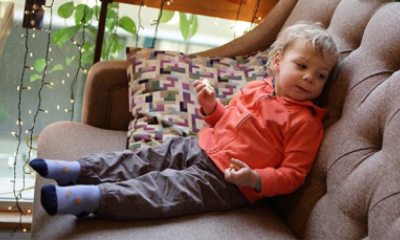 A  young child sits on a couch eating a snack