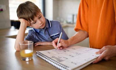 Young boy watches his mom write on a calendar