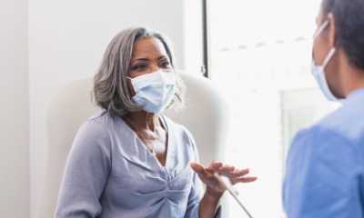 Older woman in mask talks with a doctor