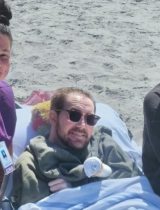 Aidan, Aidan's sister and caregiver Sandra Farris posing on the beach.
