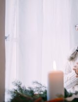 Woman with long silver hair holds a book to her chest and looks out the window
