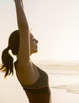 Woman stretching in the sun near the ocean waves