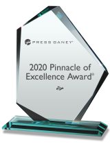 A desktop crystal glass award with the words Press Gainey 2020 Pinnacle of Excellence Award etched on the side.