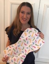 A smiling woman holding a baby pad adorned with colorful caterpillar illustrations