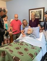 A Veteran being pinned with a medal while in a hospital bed, with family and friends around him.