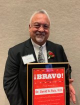 David Ruiz, M.D. smiling and displaying the Lation Health Bravo Award after it was presented to him