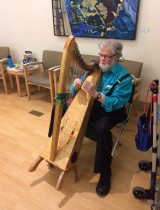 A man sitting in a waiting room playing the harp.