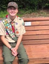 Eagle Scout sitting on a bench outside