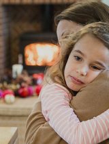 Sad young girl hugging her mom during the holidays
