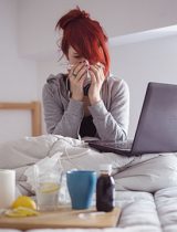 young woman blowing nose into a tissue