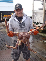 A fisherman in Alaska holds up a giant king crab