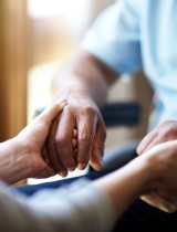 Two people hold hands while sitting