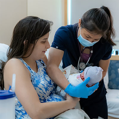 A PeaceHealth resident provider examines a newborn baby with mother sitting close by