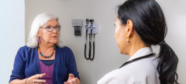 A PeaceHealth Heart & Vascular care provider speaks with a patient in a clinic setting.