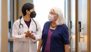 A PeaceHealth cardiovascular provider walks through the halls with a patient