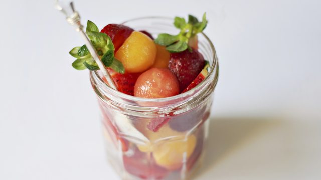 Small fruit salad in a clear cup on white background