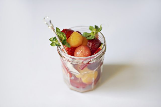 Small fruit salad in a clear cup on white background