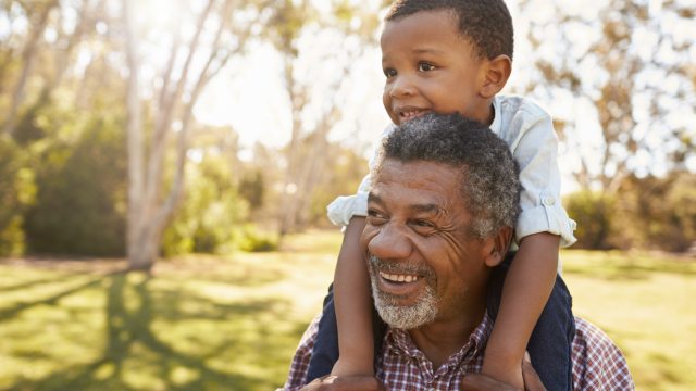 Older man smiling with grandchild sitting on his shoulders