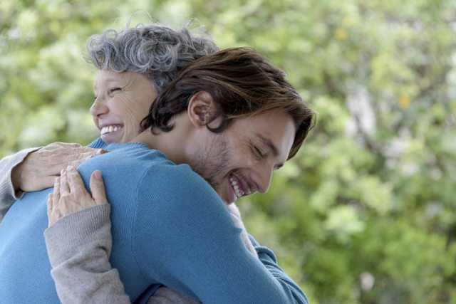 Older woman hugs a young adult man