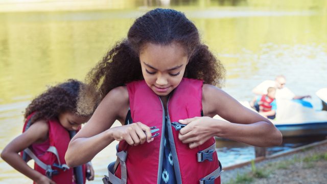 Two children put on life vests next to a lake