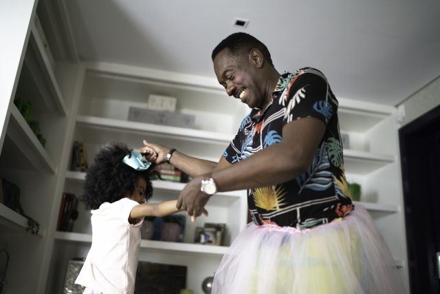 A father in a tutu, with his daughter, dance and laugh at home
