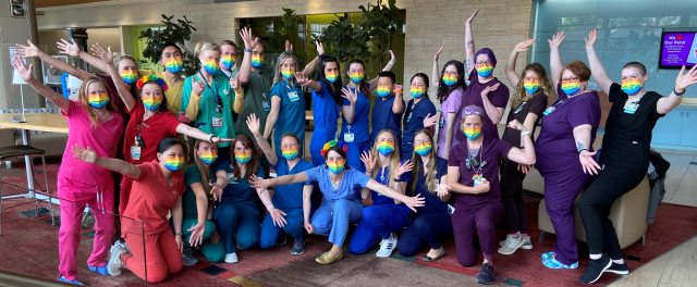 A group of nurses wearing rainbow pride scrubs poses for the camera at Firstenberg Tower