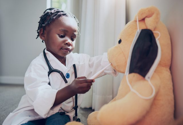 Young girl plays doctor with teddy bear