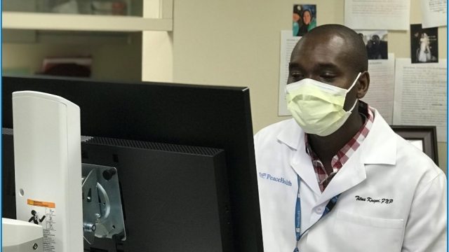 Titus Kosgei, DNP, works at a computer in the clinic