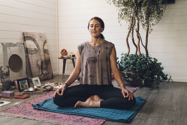 Tessa performs yoga on a mat in a living room