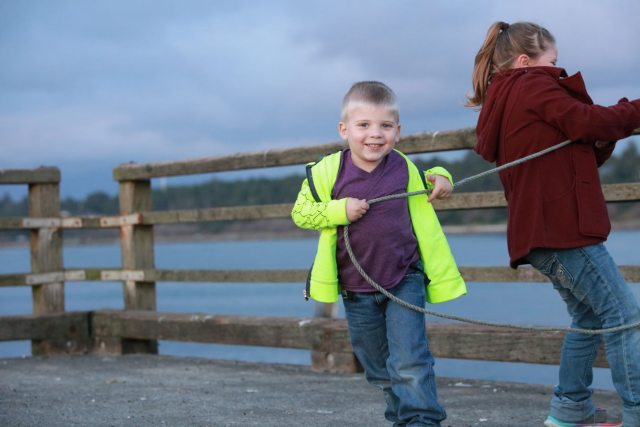 Smiling young boy pulls on a fishing line on pier