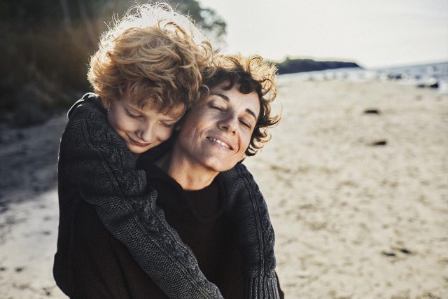 Child embracing a woman on a beach