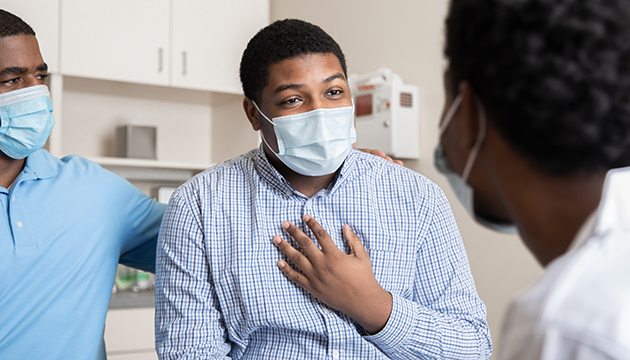 Adult parent and teen patient speak with a physician in an exam room
